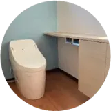 最新の温水洗浄便座を備えたトイレ。木目調のカウンターと収納付き。