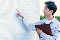 外壁を指差しながら点検するスタッフ