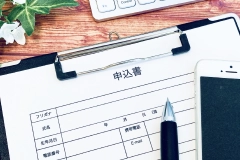 申込書とボールペン、スマートフォンの写真