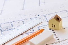 住宅設計図と模型、定規と鉛筆が置かれた作業台