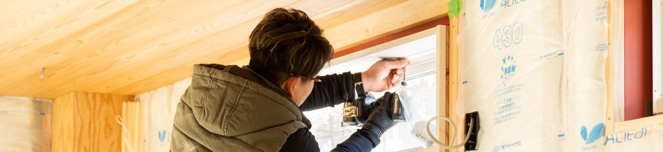 木造住宅の室内工事を行っている作業員。断熱材と木材が見える工事中の様子