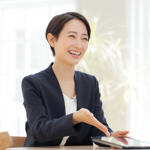 タブレットを手にした女性スタッフが笑顔で相談対応している様子